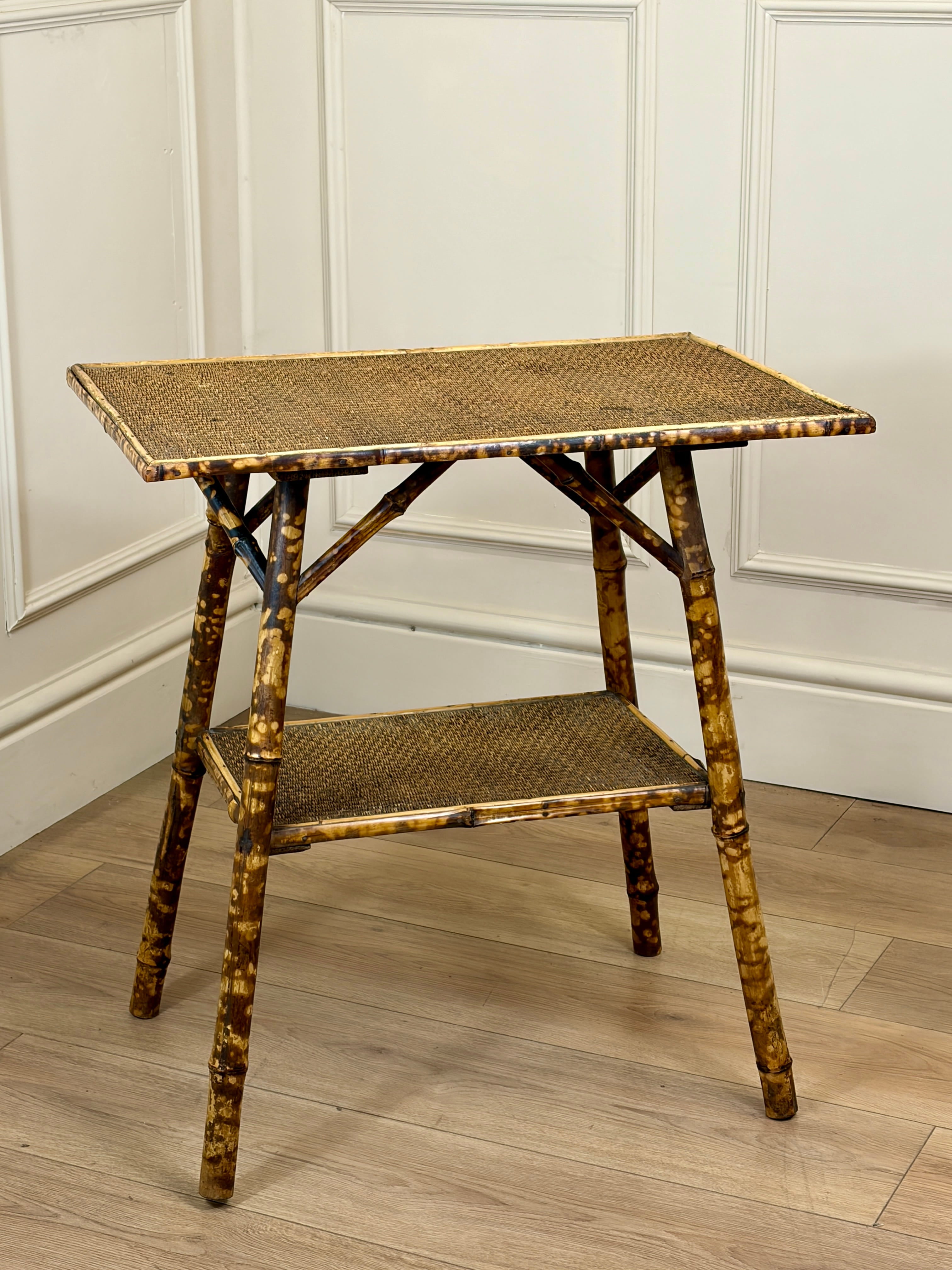 Bamboo side table with woven top and shelf against a white paneled wall.