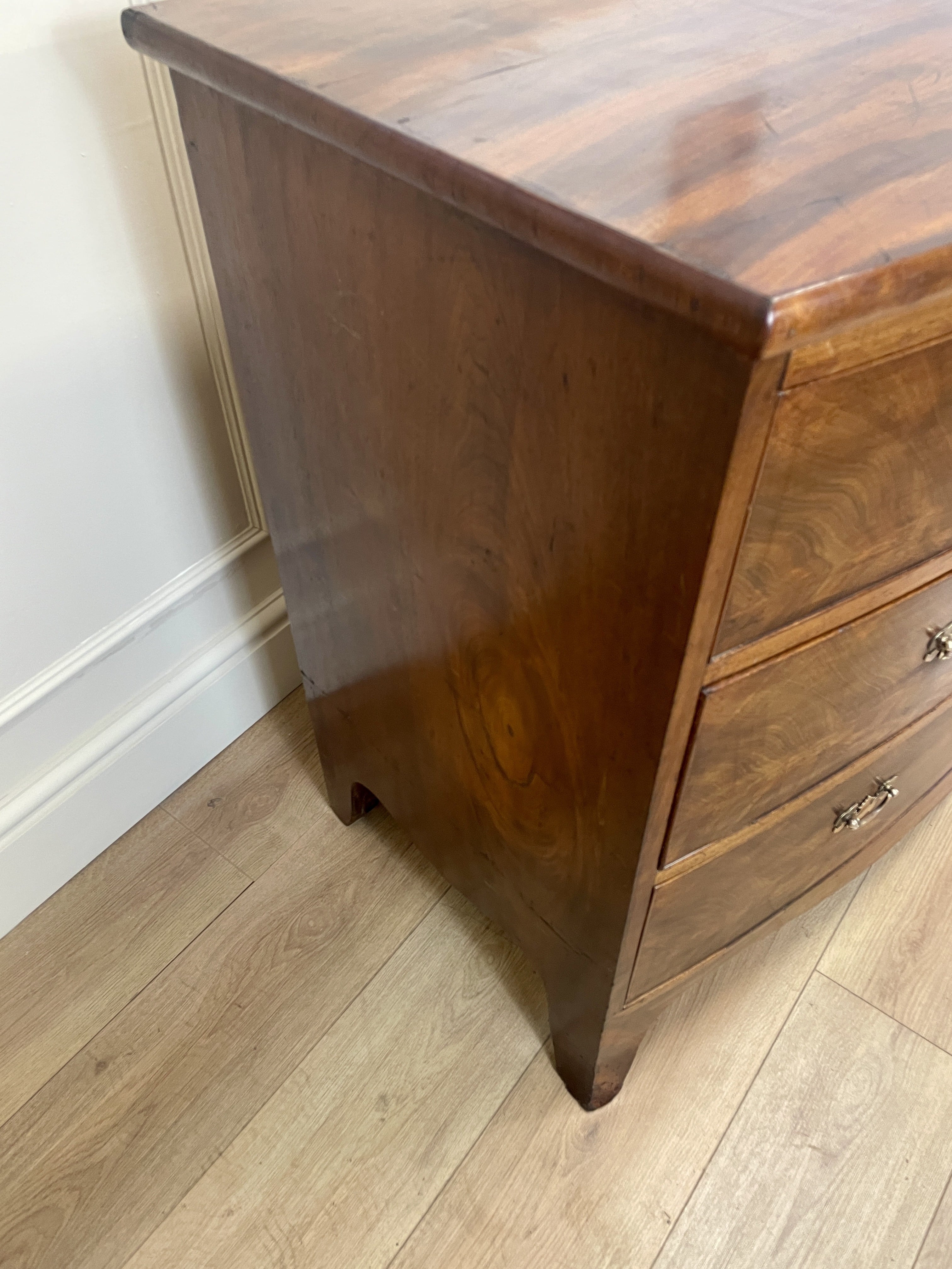 Wooden dresser with three drawers on a wooden floor against a white wall.