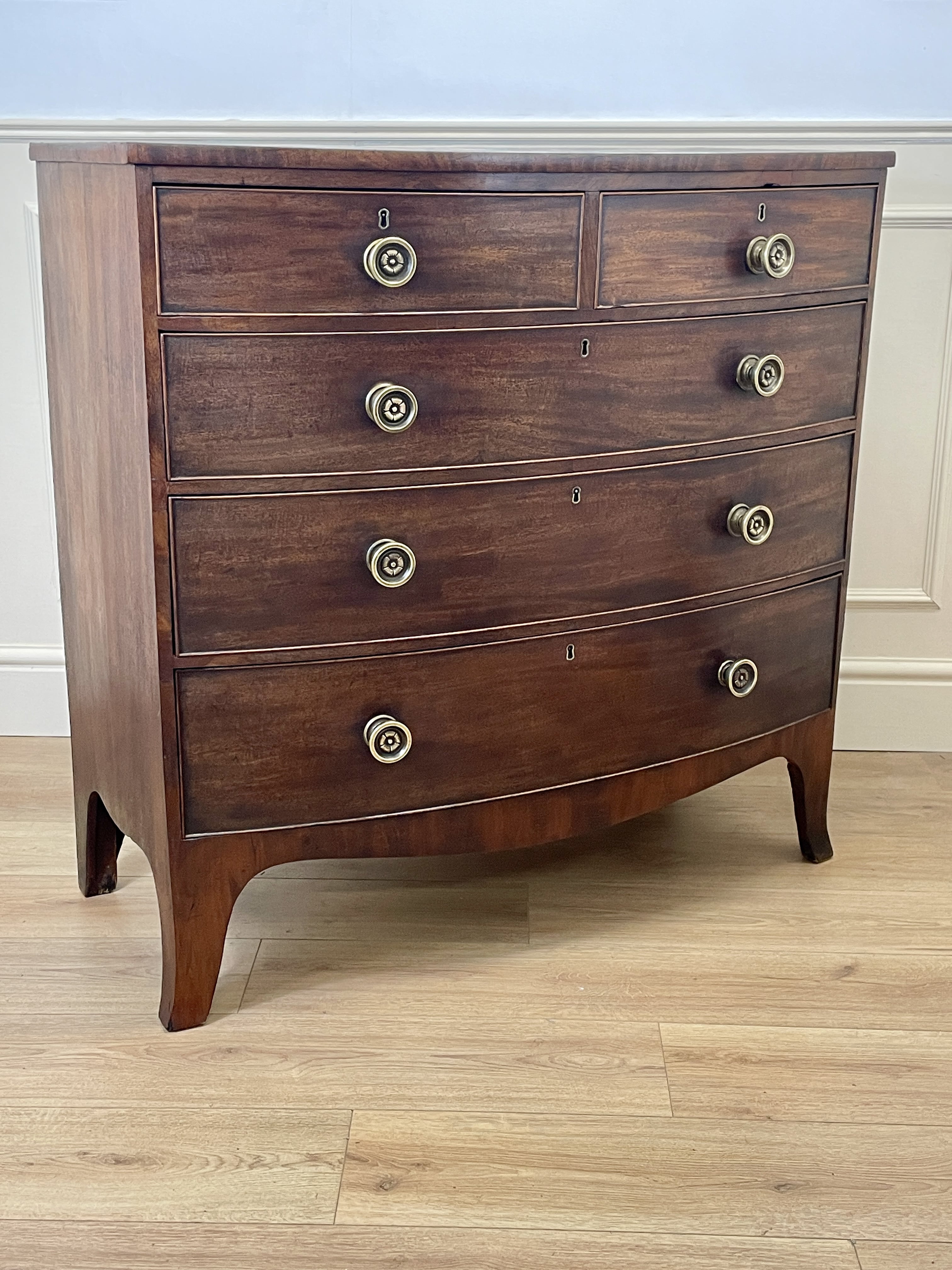 Wooden dresser with brass knobs on a wooden floor.