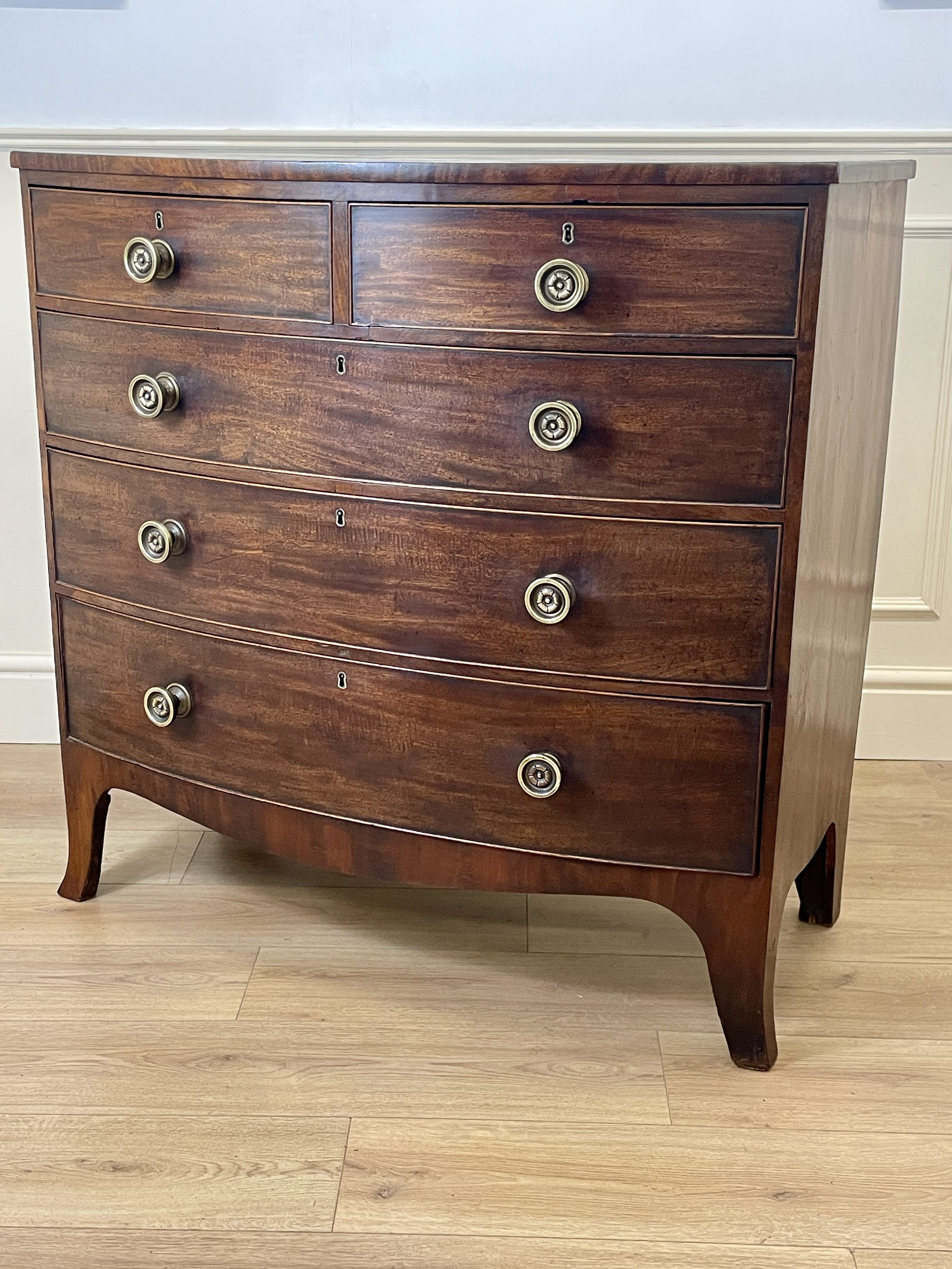 Wooden dresser with four drawers on a wooden floor.