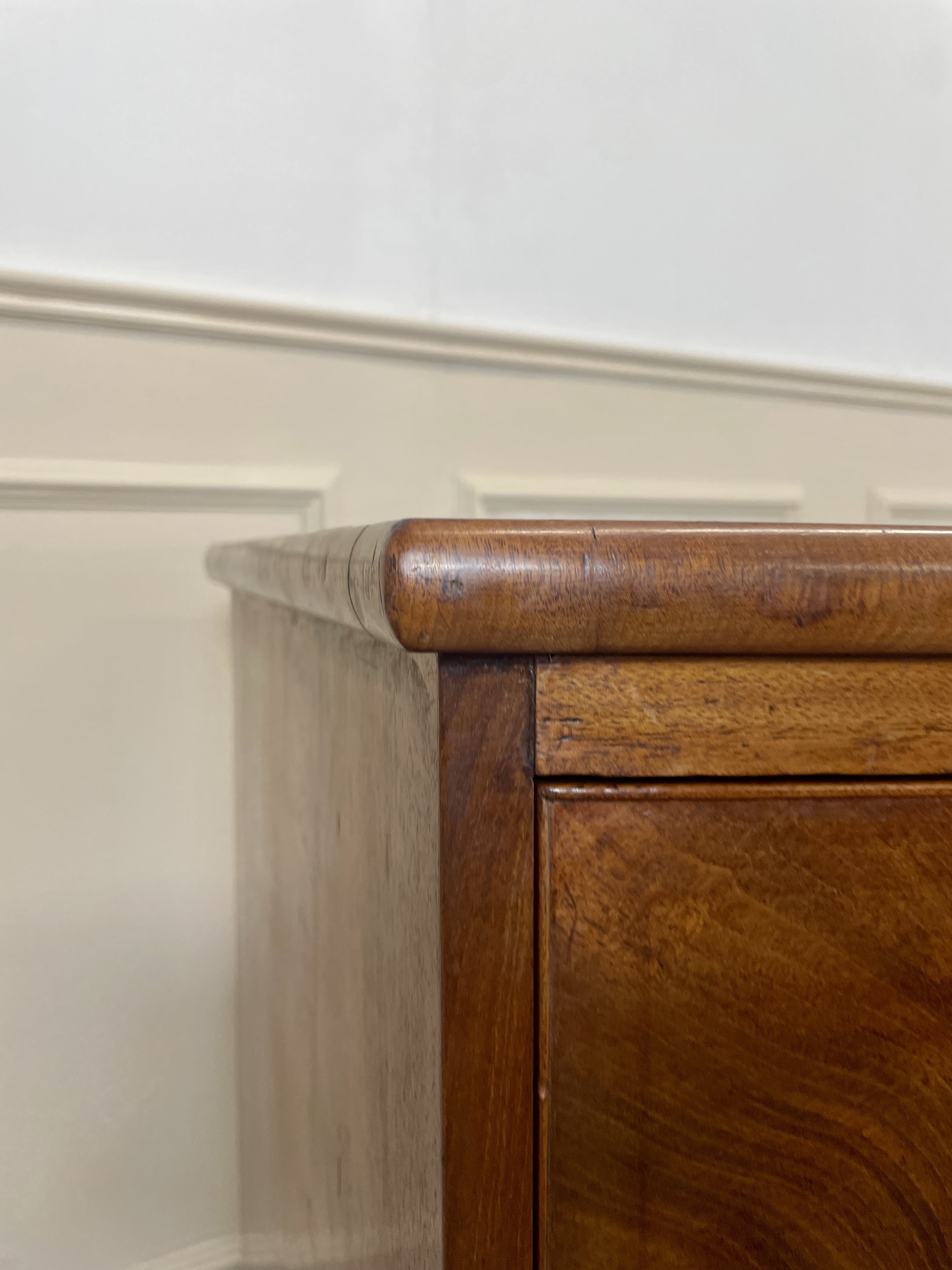 Close-up of a wooden cabinet corner with a white wall background