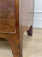 Close-up of a wooden piece of furniture with a visible crack on a light wood floor.