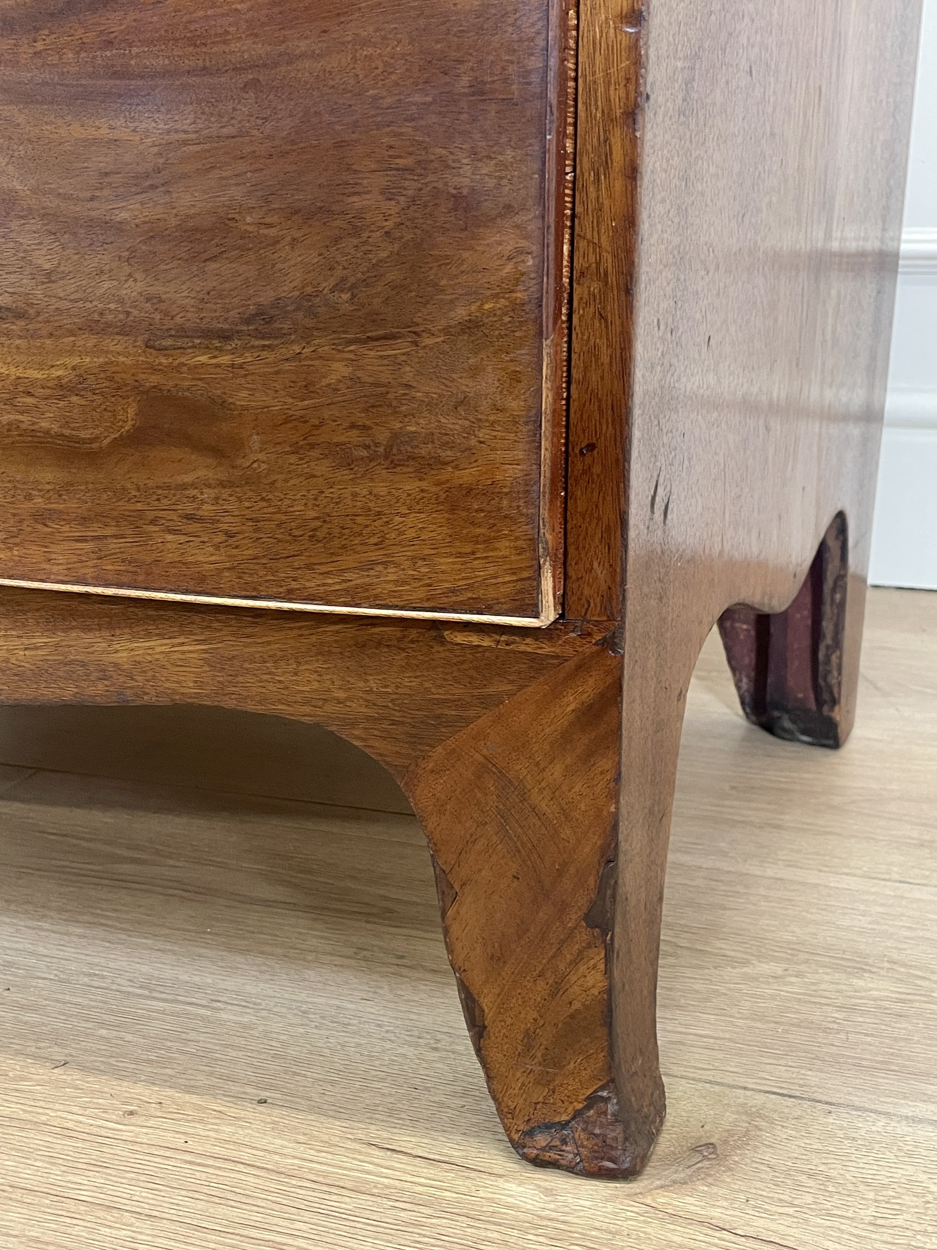 Close-up of a wooden drawer with a visible grain pattern on a light wood floor.