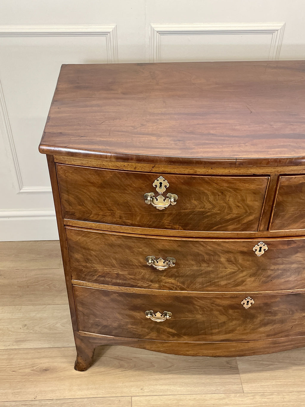 Wooden dresser with three drawers on a wooden floor against a white wall.