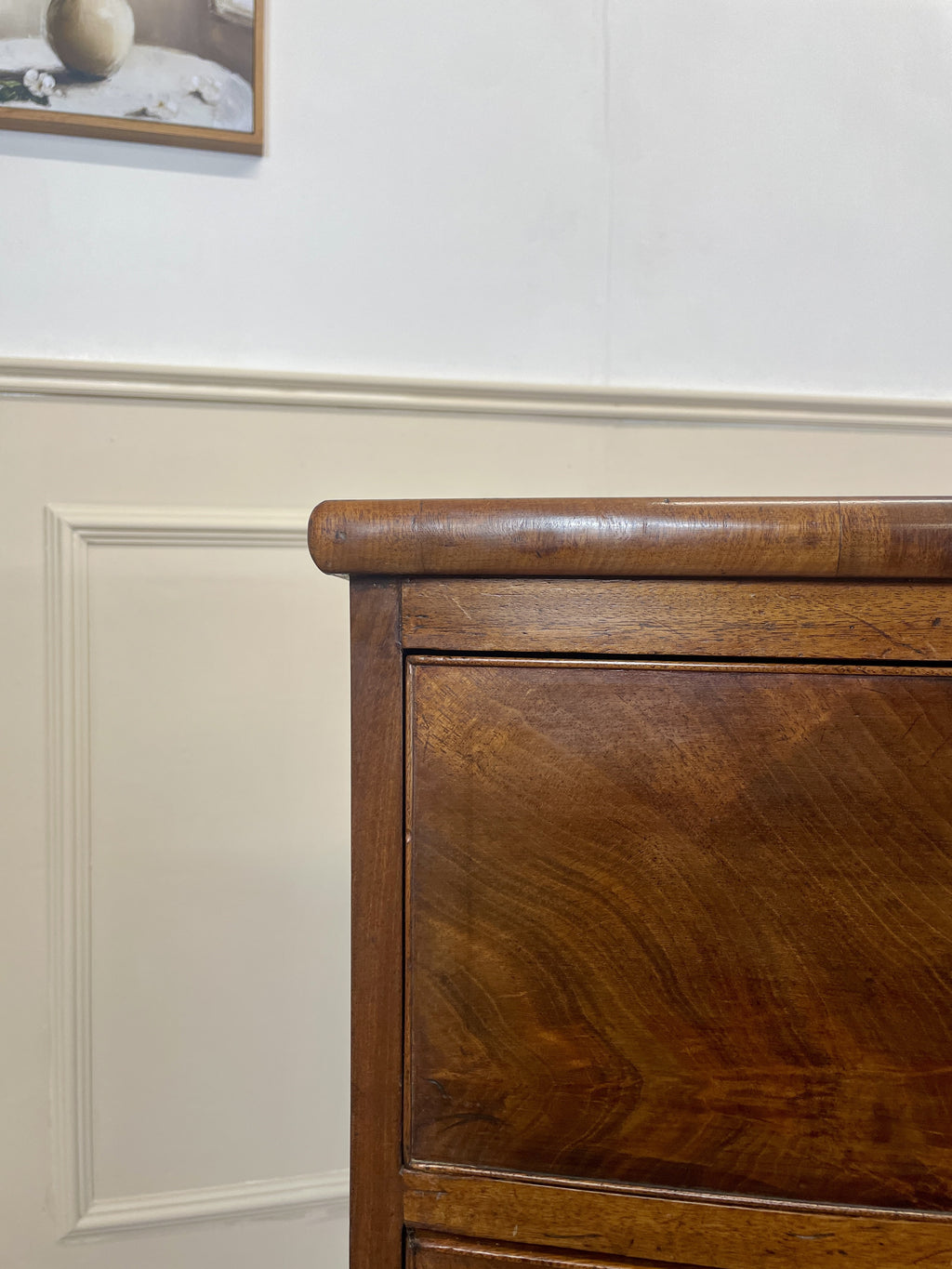 Wooden dresser against a white wall with decorative molding
