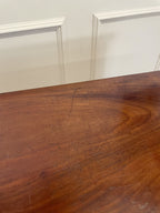 Wooden table with visible scratches against a white paneled wall