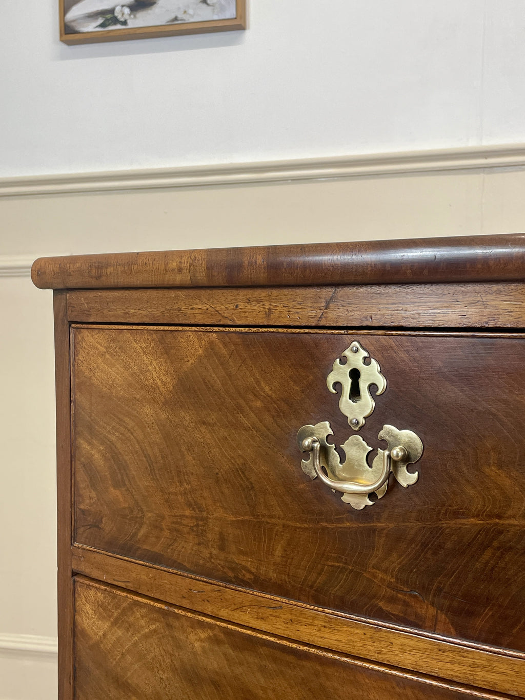 Close-up of an antique wooden dresser with a brass handle.