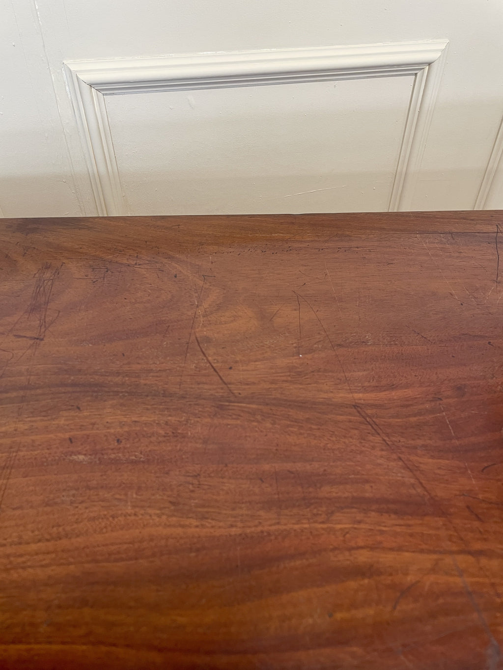 Wooden surface with a white baseboard in the background