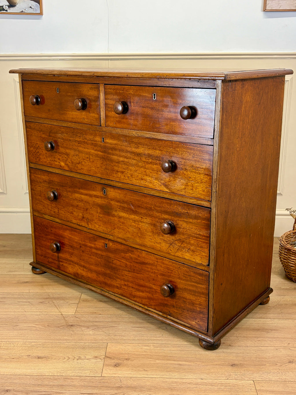 Wooden dresser with multiple drawers on a wooden floor.