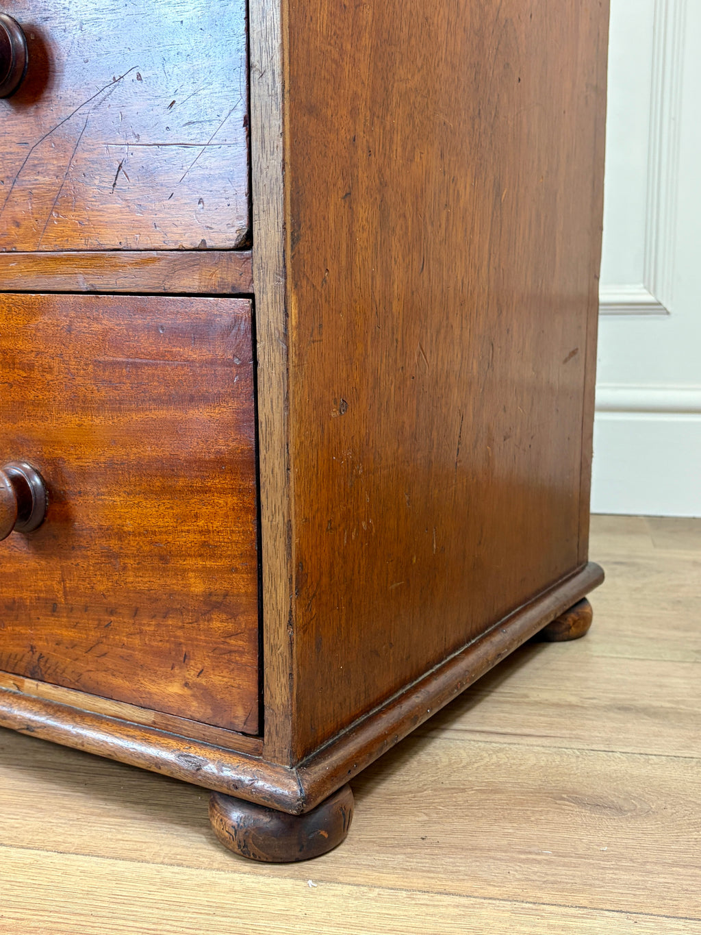Close-up of an old wooden dresser with visible wear on a wooden floor.