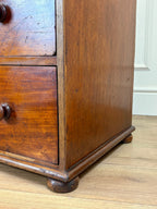 Close-up of an old wooden dresser with visible wear on a wooden floor.
