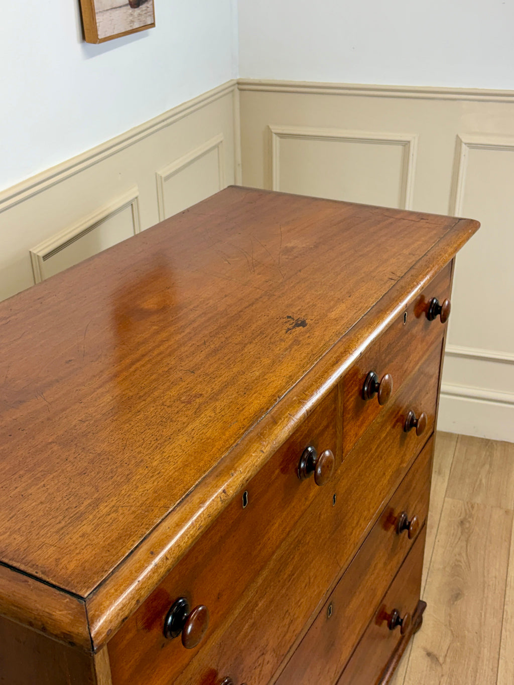 Wooden dresser with multiple drawers in a room with white walls and wooden floor.