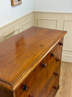 Wooden dresser with multiple drawers in a room with white walls and wooden floor.