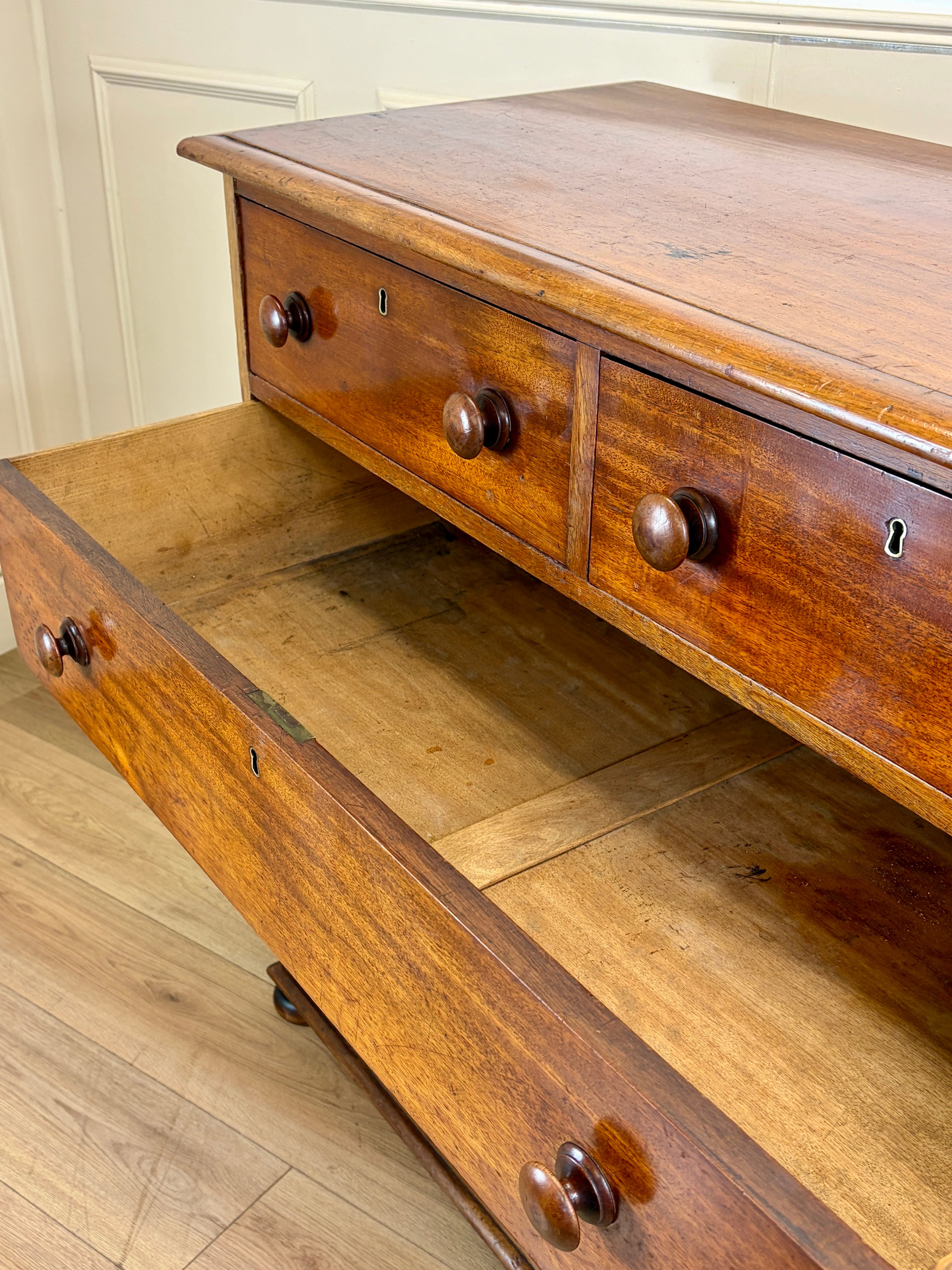 Wooden dresser with open drawer on a wooden floor