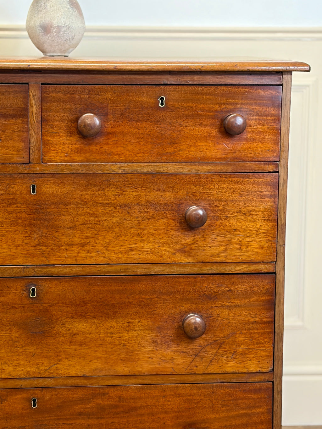 Wooden dresser with three drawers and metal knobs against a white wall.