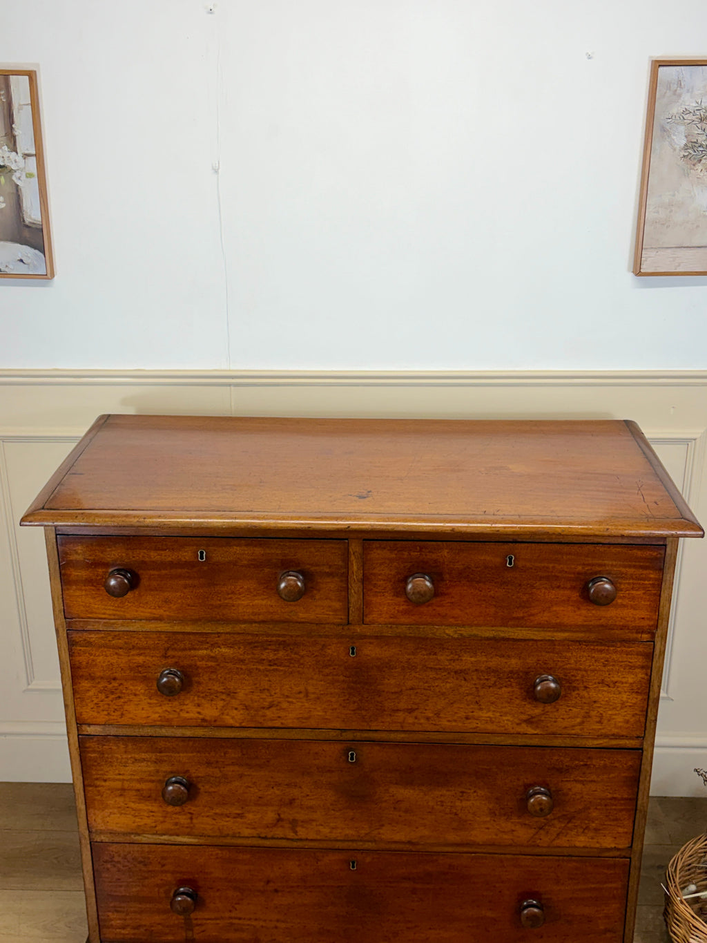 Wooden dresser with four drawers against a white wall.