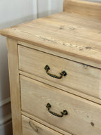 Wooden dresser with two drawers and metal handles against a white wall.