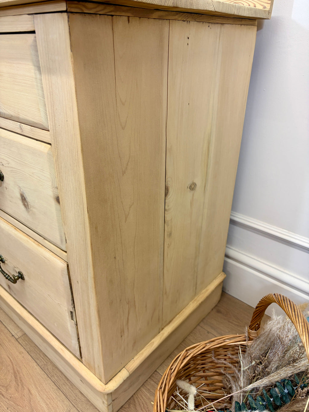 Wooden dresser with a wicker basket on a wooden floor.
