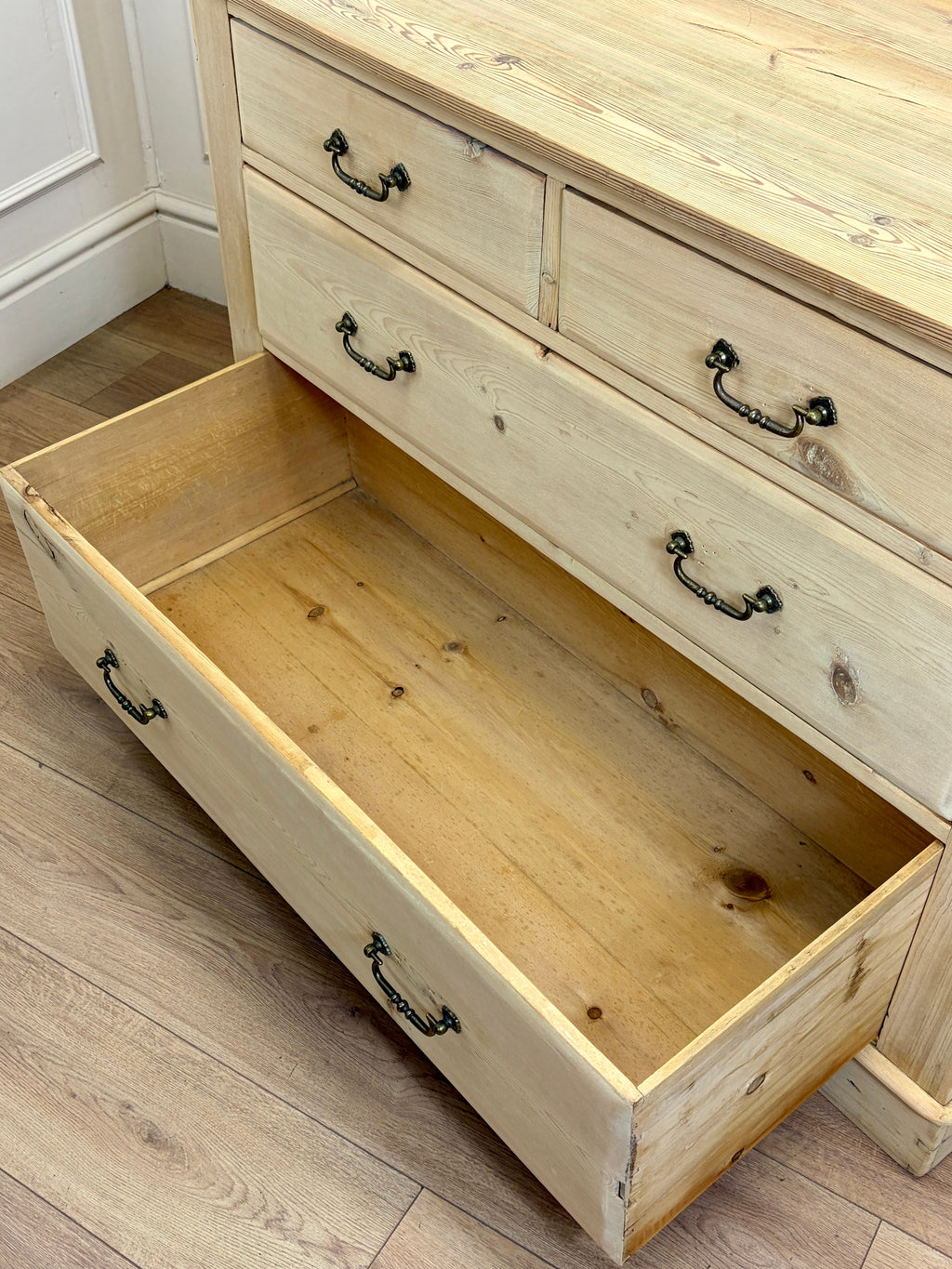Wooden dresser with open drawer on a wooden floor