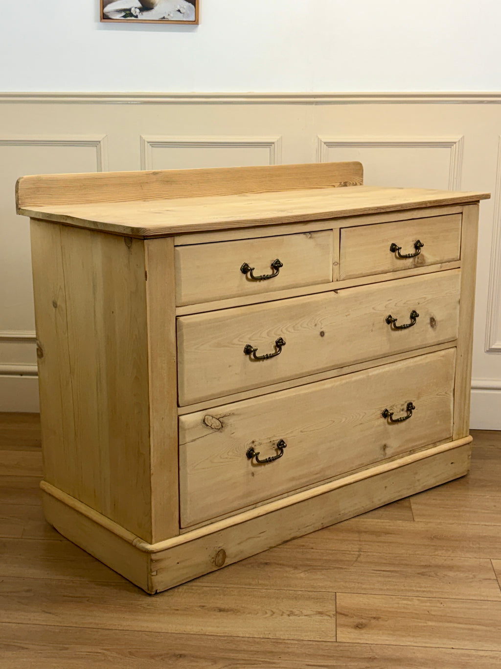 Wooden dresser with four drawers on a wooden floor.