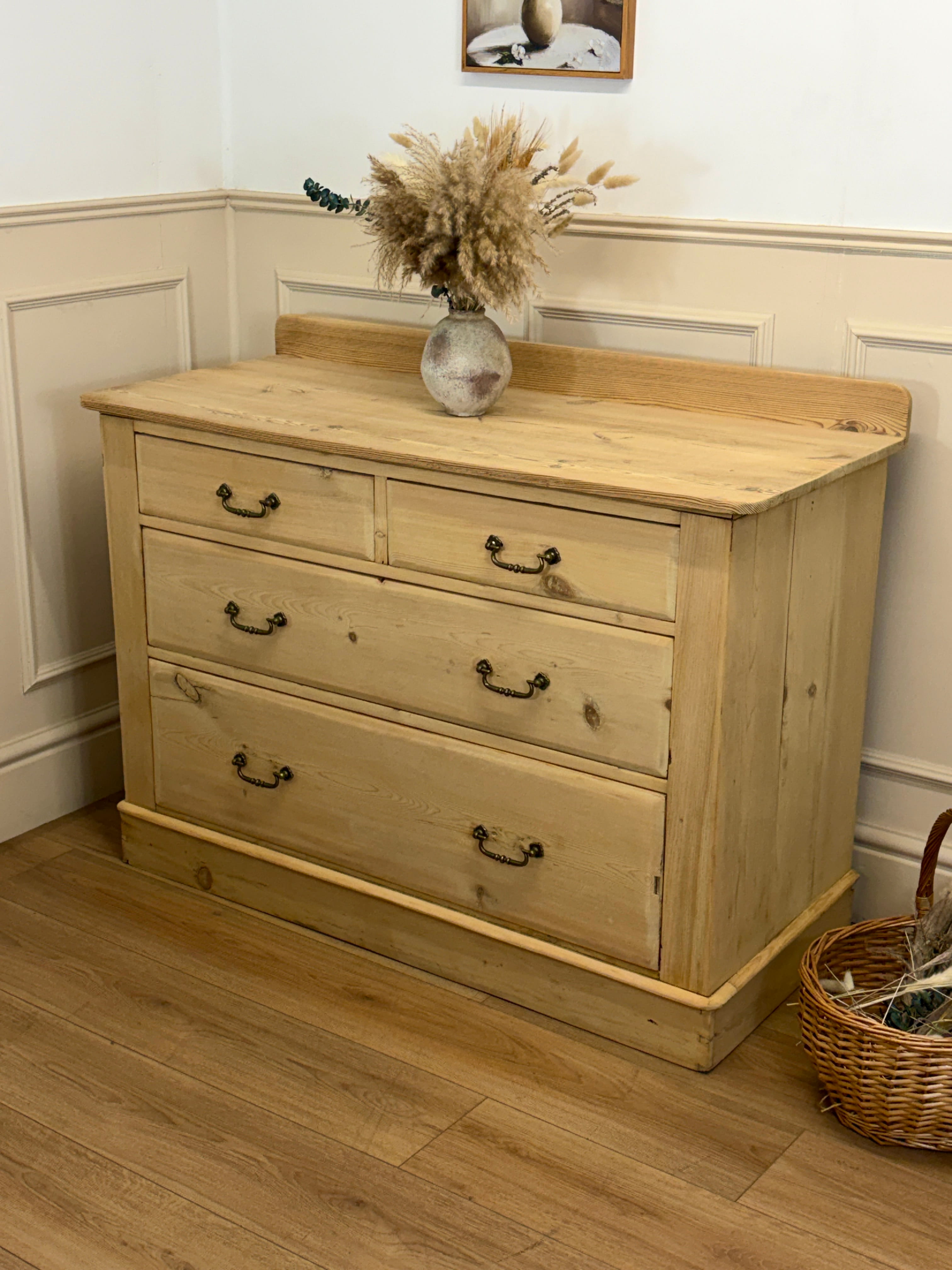 Wooden dresser with three drawers in a room with white walls and wooden floor.