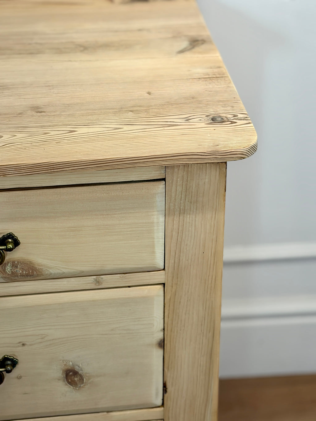 Wooden dresser with two drawers against a white wall.