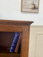 Wooden shelf with a blue book and a brown book, framed picture on the wall.