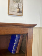 Wooden fireplace with two books inside, framed picture above on white wall