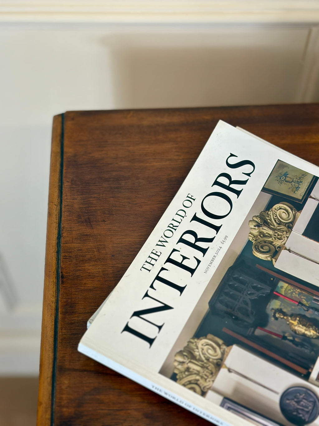 Book titled 'The World of Interiors' on a wooden surface