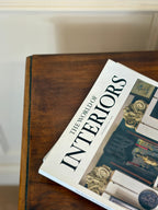 Book titled 'The World of Interiors' on a wooden surface