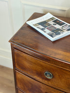 Wooden dresser with a newspaper on top against a white wall.