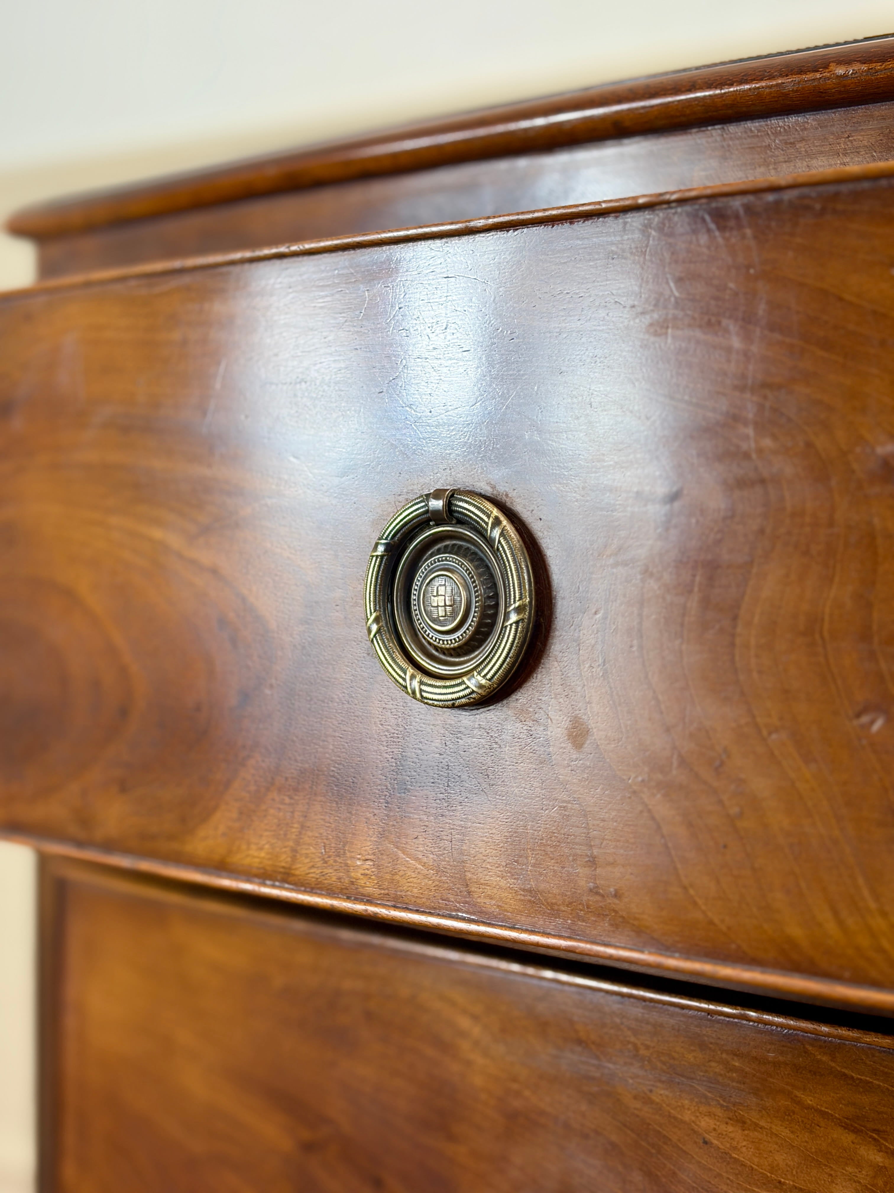 Close-up of a wooden drawer with a brass handle on a light-colored wall.