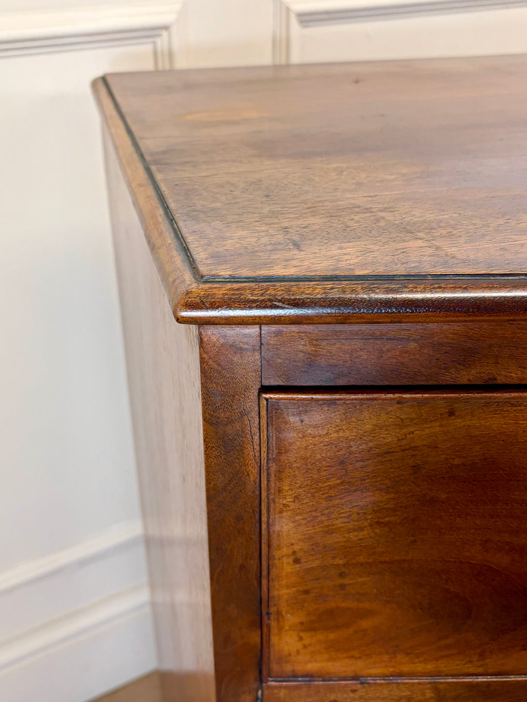 Wooden dresser with a worn finish against a neutral wall.