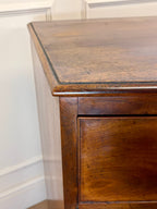 Wooden dresser with a worn finish against a neutral wall.