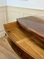 Wooden boat on a wooden floor with white paneled walls.