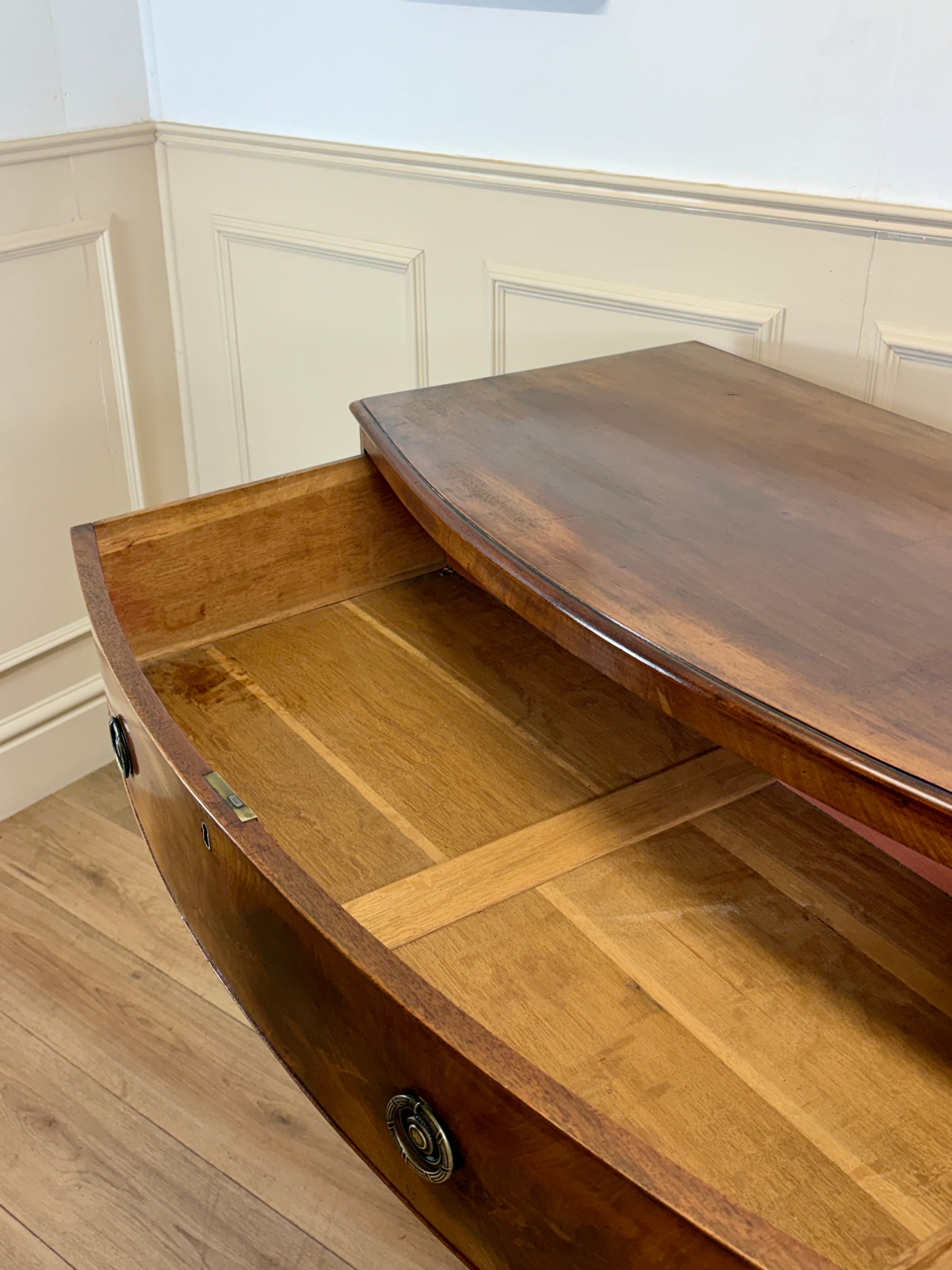 Wooden boat on a wooden floor with white paneled walls.