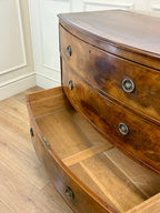 Wooden dresser with curved design and decorative buttons on a wooden floor.