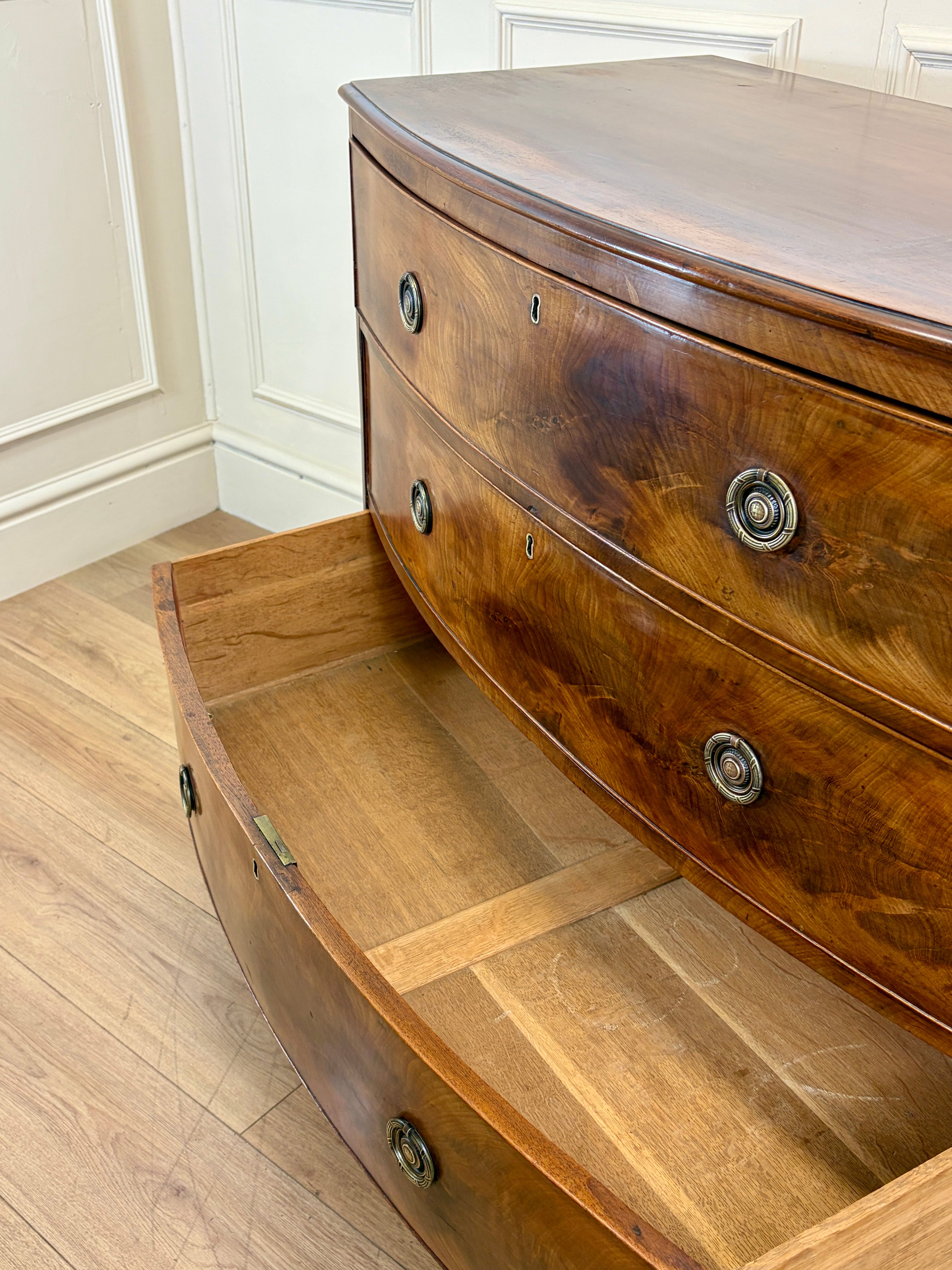 Wooden dresser with curved design and decorative buttons on a wooden floor.
