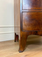 Wooden cabinet with a curved leg on a wooden floor against a white wall