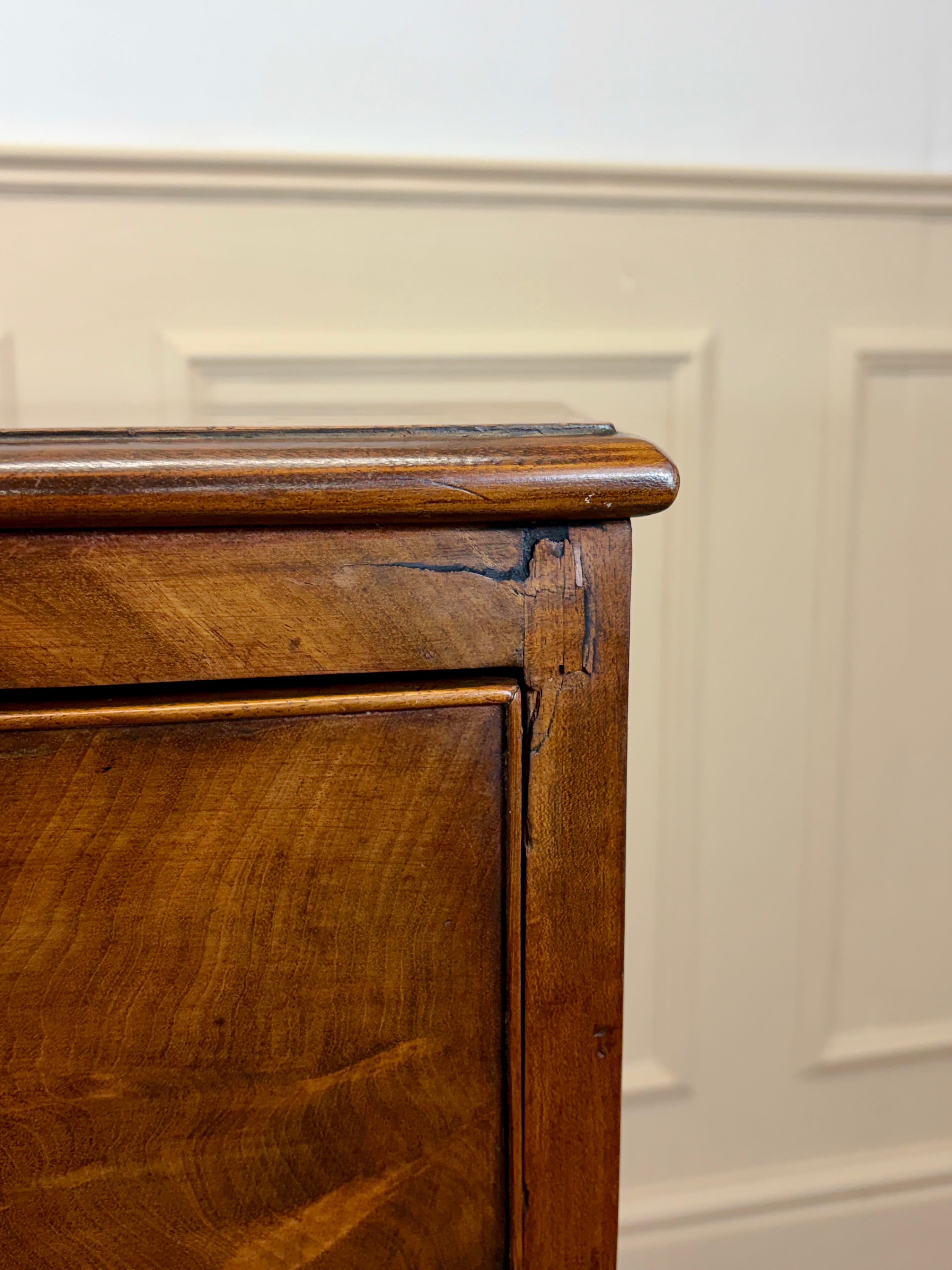 Close-up of a wooden cabinet corner with a white paneled wall background