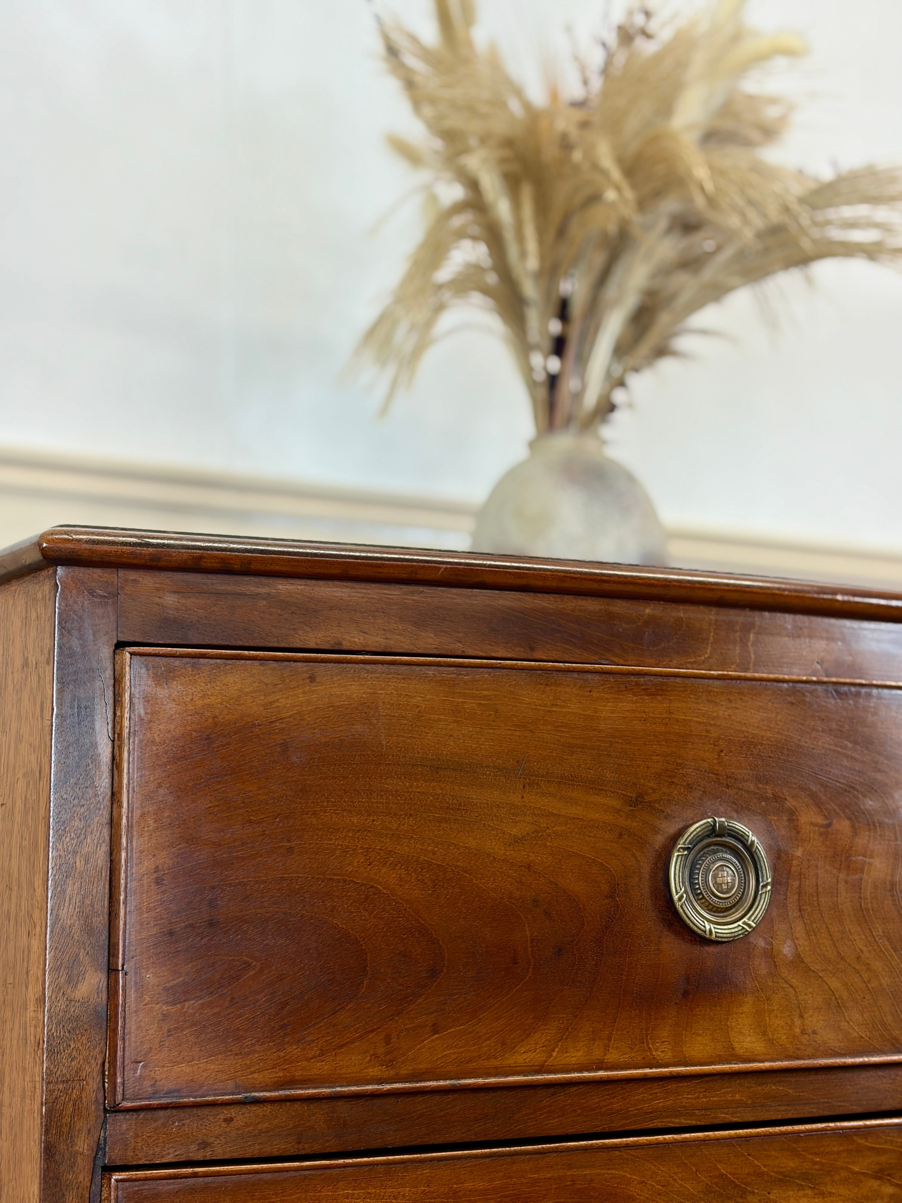 Wooden dresser with a decorative vase of dried plants on top
