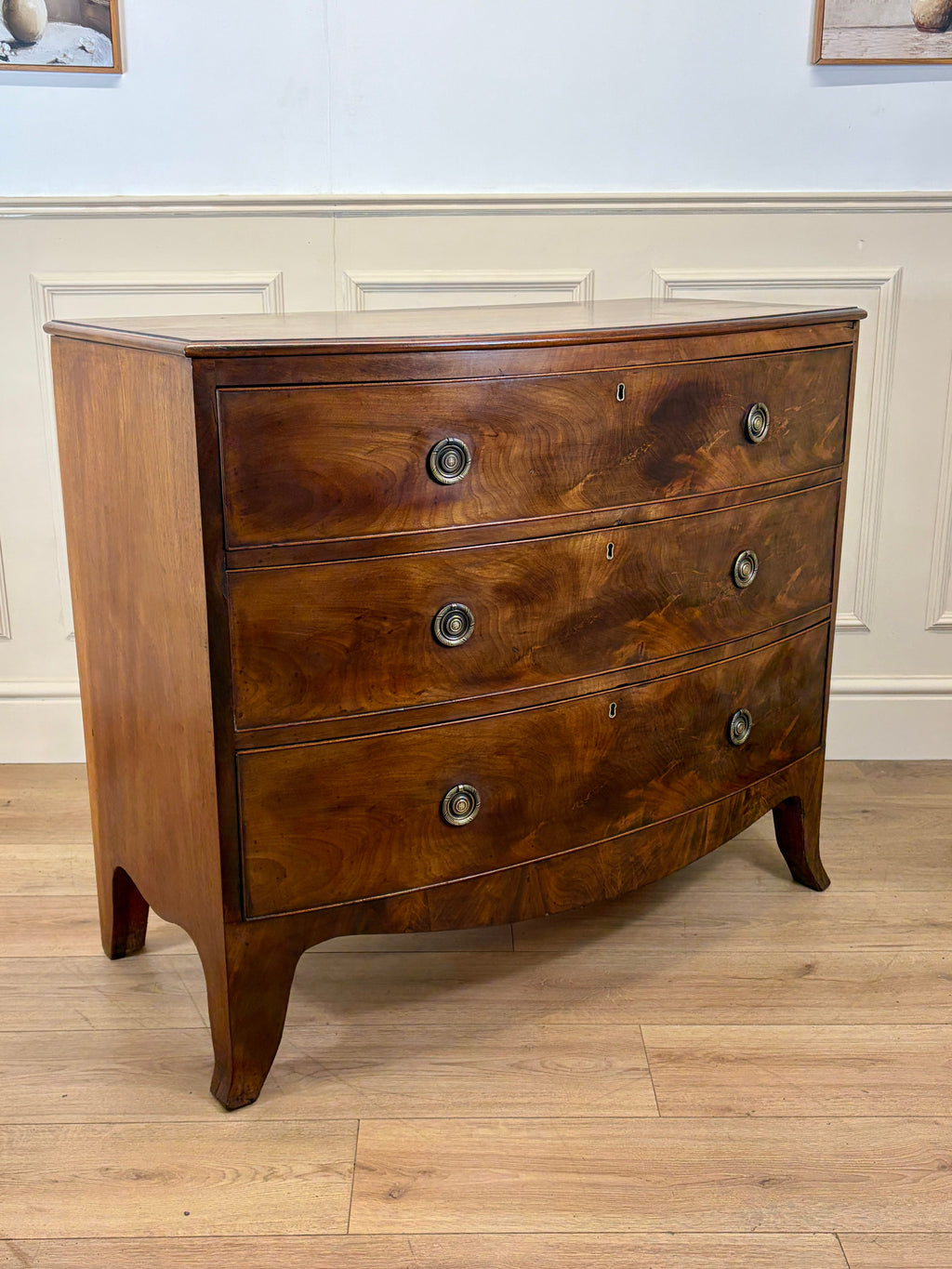 Wooden dresser with three drawers on a wooden floor against a white wall.