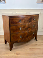 Wooden dresser with three drawers on a wooden floor against a white wall.