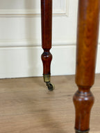 Close-up of a wooden leg with a caster wheel on a wooden floor.