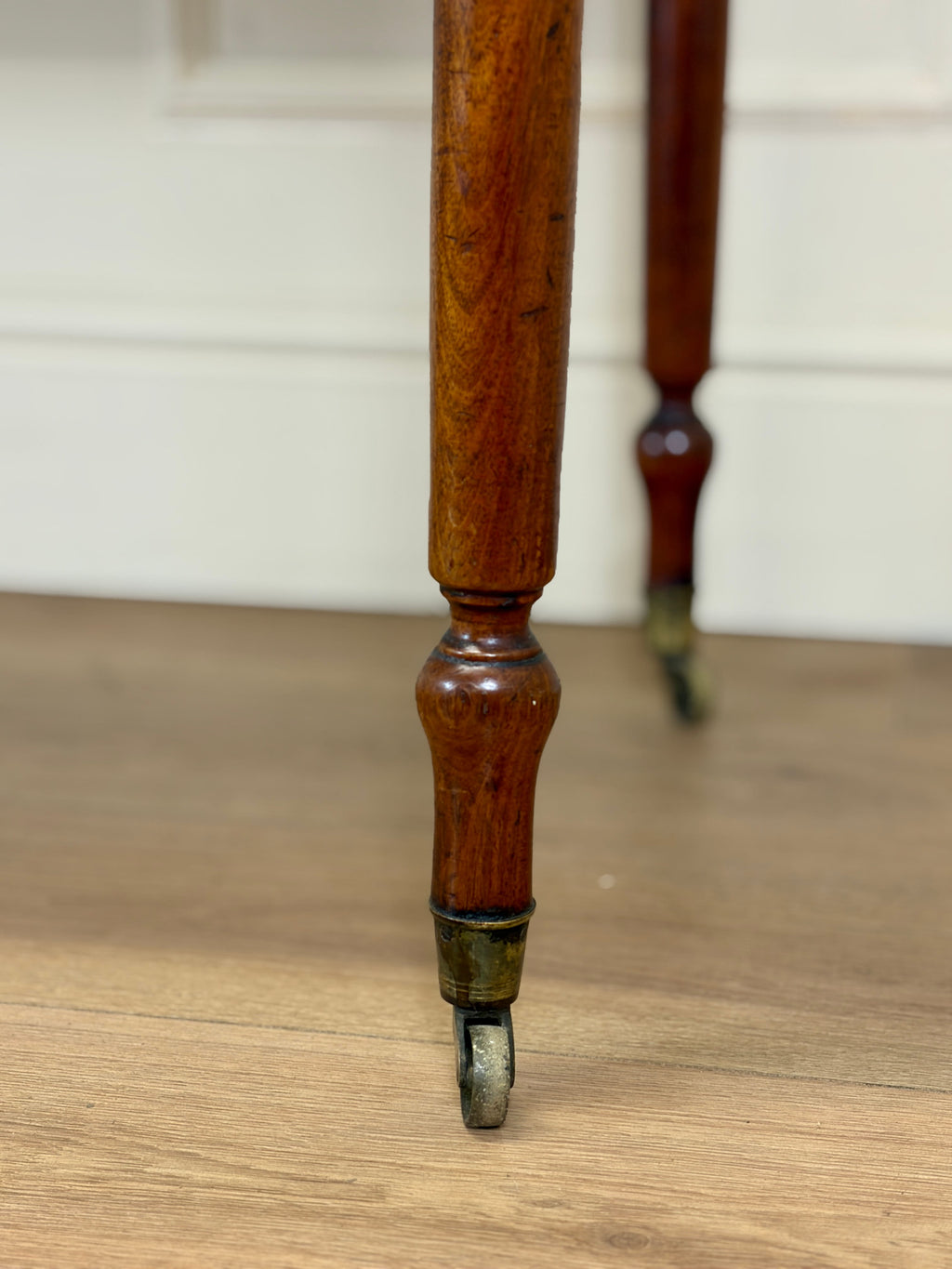 Close-up of a wooden leg with a metal foot on a wooden floor.