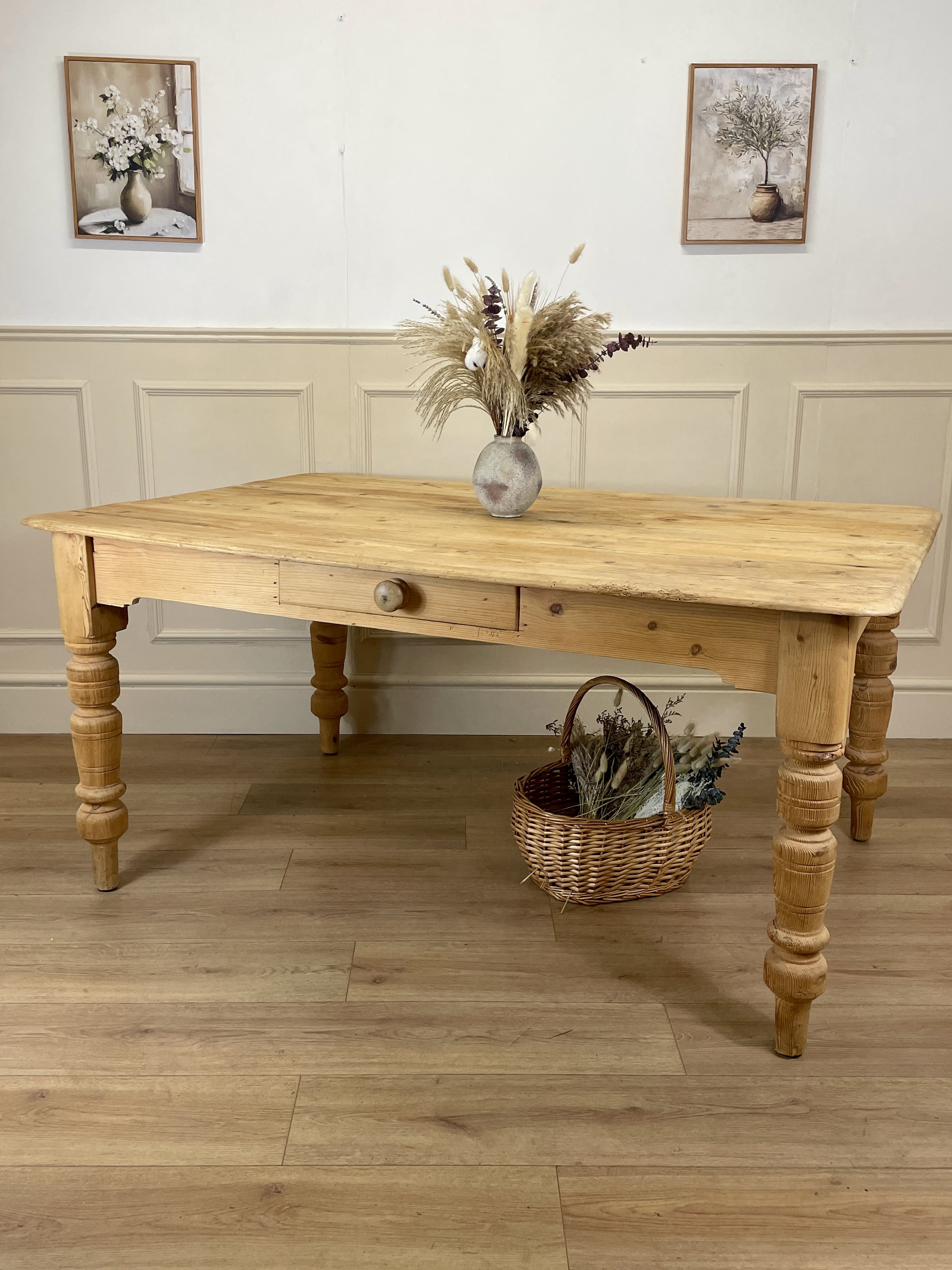 Wooden table with decorative items on a wooden floor, framed by wall art.
