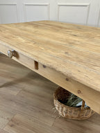 Wooden table with a woven basket underneath on a wooden floor.