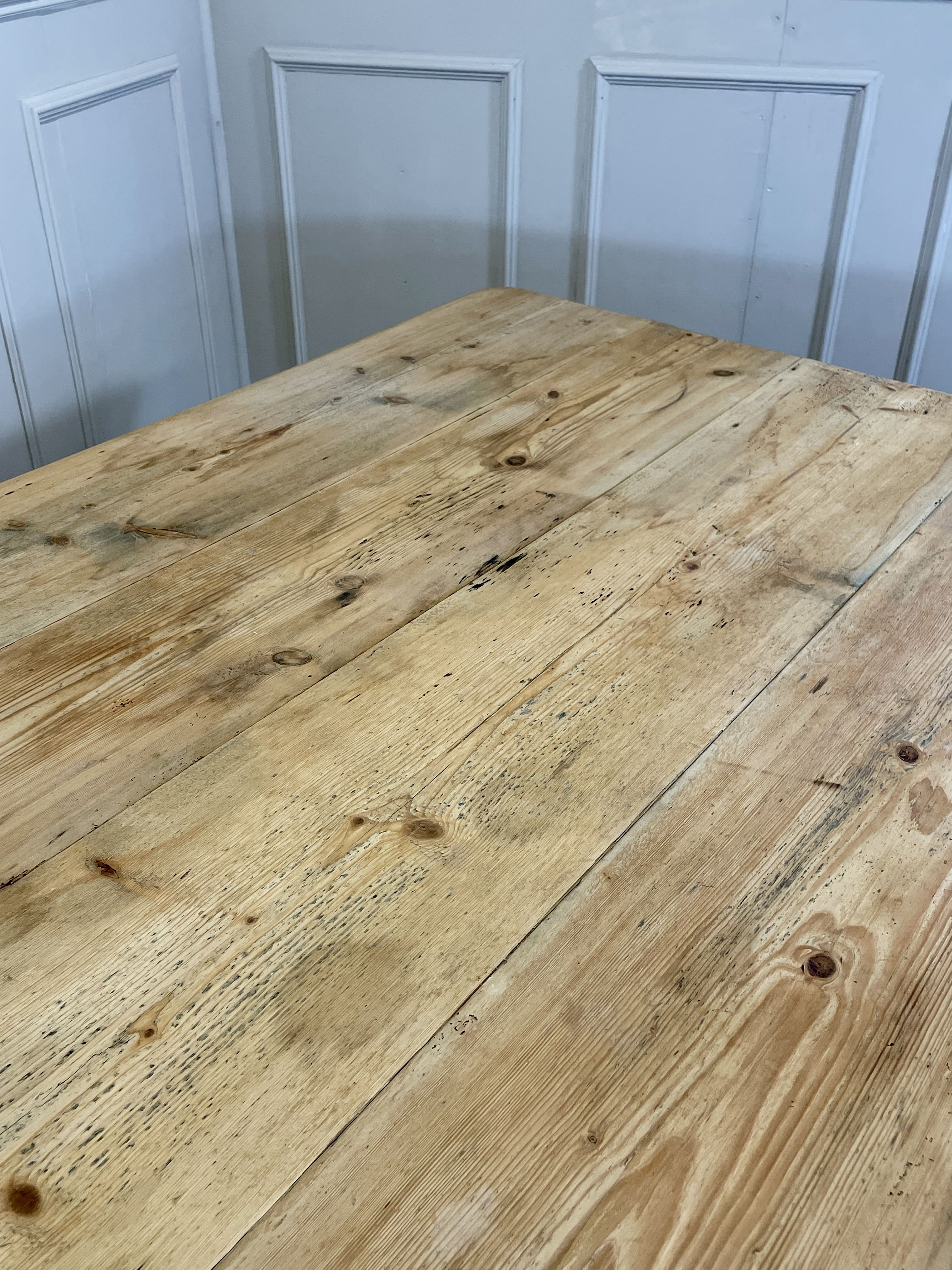 Wooden table with a rustic finish against a light blue paneled wall.