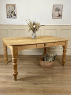 Wooden table with decorative items in a room with wainscoting and framed pictures.