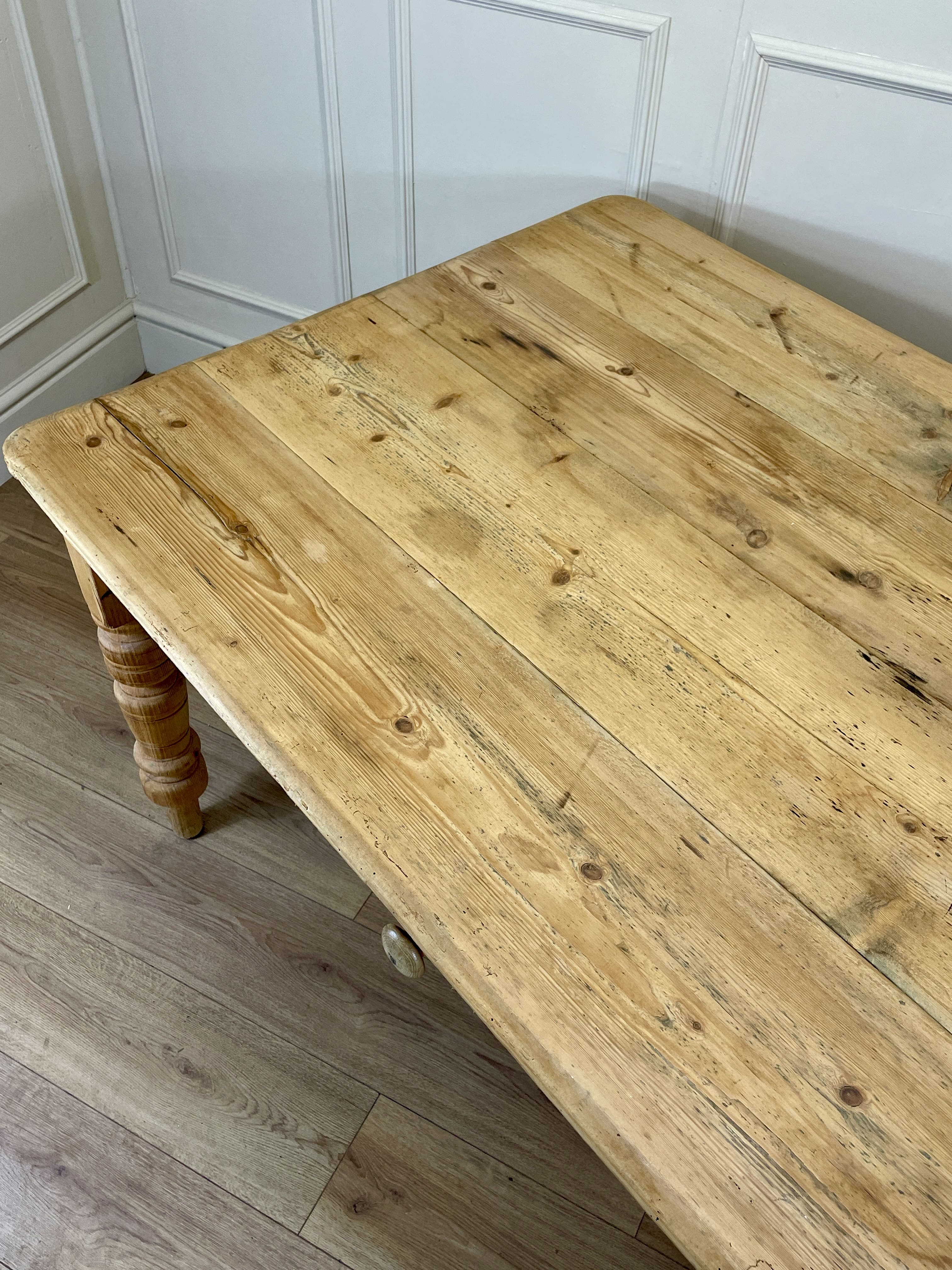 Wooden table with a rustic finish in a room with white paneled walls.